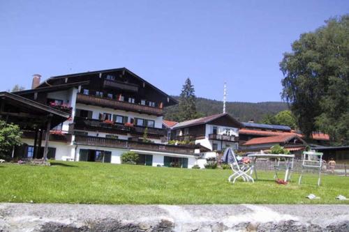 a building with a table and chairs in the grass at Ferienwohnungen am See _ Hinterseer in Schliersee