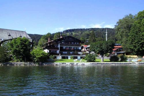 a large house sitting on the shore of a lake at Ferienwohnungen am See _ Hinterseer in Schliersee