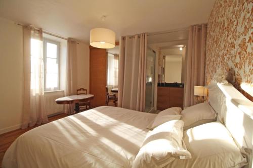 a bedroom with a large white bed and a table at La maison d'eugénie in Jourgnac