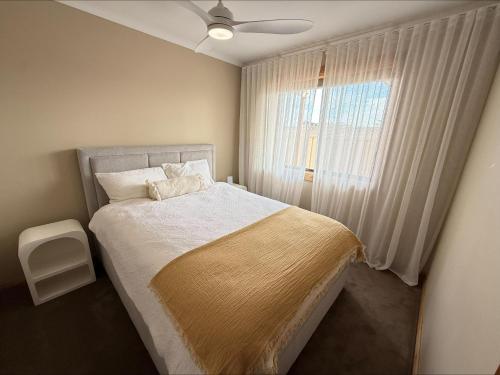 a bedroom with a bed with a ceiling fan and a window at B & B on Yorkes in Edithburgh