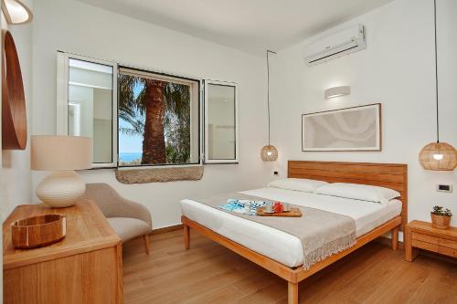a bedroom with a bed and a chair and a window at Villa Gabbiano - Scopello-Villas in Scopello