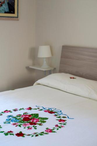 a white bed with a flower blanket on it at Nosside & Saffo Guesthouse in Amantea