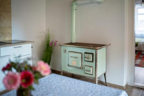 a small green stove in a kitchen with flowers at Kiskörtés Vendégház Óhuta in Háromhuta