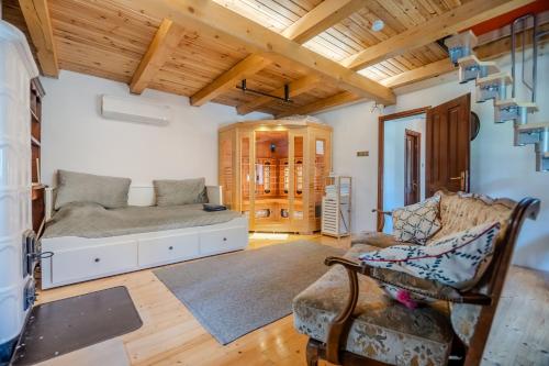 a living room with a bed and a chair at Kiskörtés Vendégház Óhuta in Háromhuta