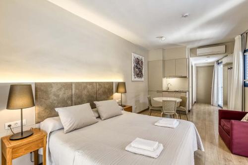 a bedroom with a large bed and a living room at Aparthotel 1904 in Figueres