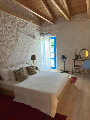 a bedroom with a large white bed with a stone wall at Villa Bakola in Sívros