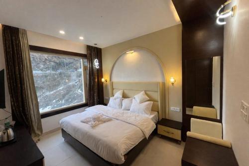 a bedroom with a large bed with a large window at Hotel Shaurrat in Shimla