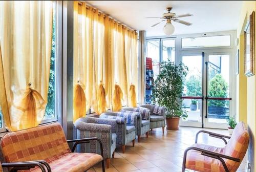 a waiting room with a row of chairs and windows at Hotel Cesari in Rimini