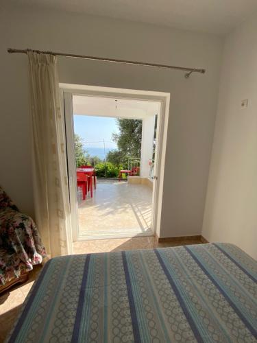a bedroom with a bed and a door leading to a patio at Ionian Sunset Drymades in Gjilek
