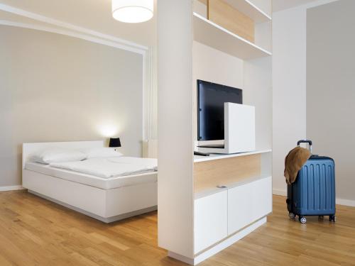 a bedroom with a bed and a television and a suitcase at smartments Hamburg Aussenalster in Hamburg