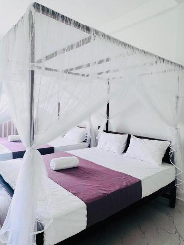a bedroom with a white bed with a white canopy at Hotel Elysian in Udawalawe