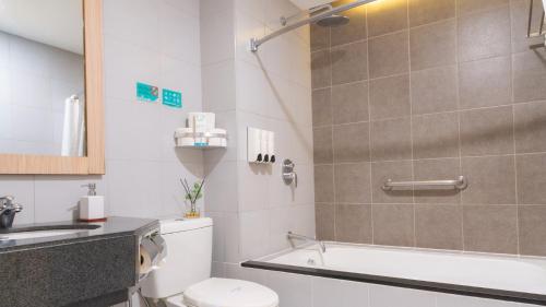 a bathroom with a toilet and a sink and a bath tub at Microtel by Wyndham UP Technohub in Manila