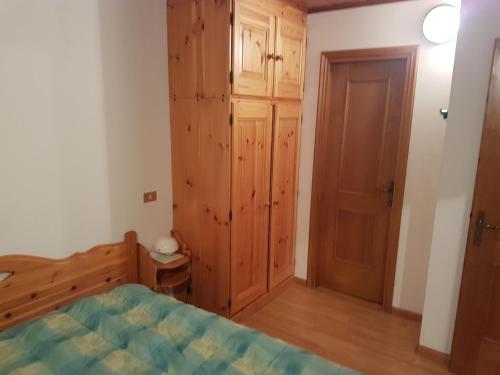 een slaapkamer met een bed en een houten kast bij Appartamento Camporosso in Tarvisio