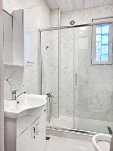 a white bathroom with a shower and a sink at Smash Hostel Batumi in Batumi