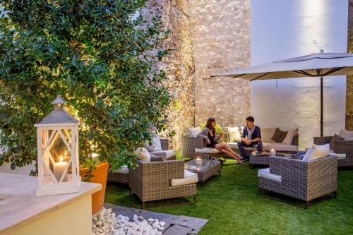 two people sitting in a patio with chairs and an umbrella at The Spring House Hotel Rome Vatican, Tapestry Collection Hilton in Rome
