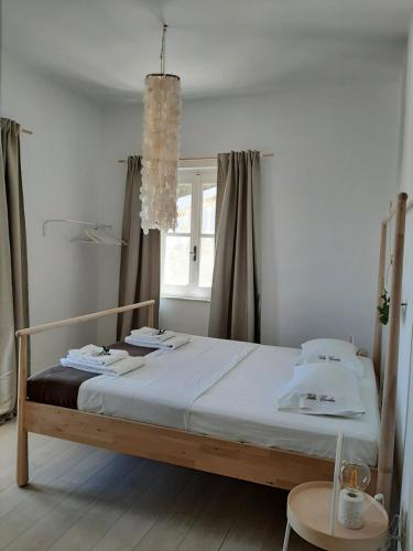 a bed in a white room with a window at Guesthouses Thomas & Cato in Vátos