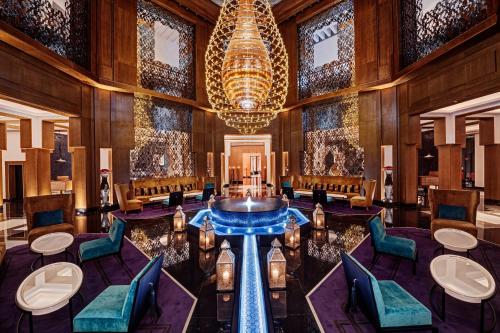 a lobby with a large chandelier and a table and chairs at Mövenpick Hotel Mansour Eddahbi Marrakech in Marrakech