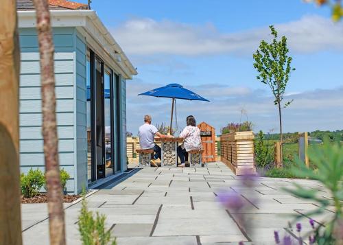 a man and woman standing under an umbrella on a patio at Penmarlam Lodge Retreat in Fowey