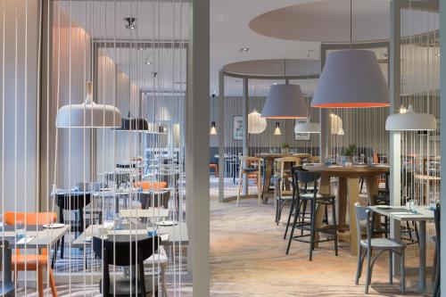 a restaurant with tables and chairs and chandeliers at Novotel Kraków City West in Kraków