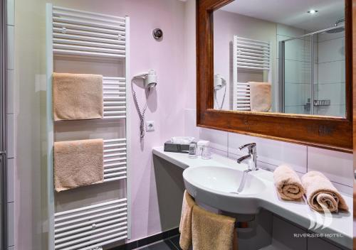 a white bathroom with a sink and a mirror at Riverside Hotel in Nordhorn