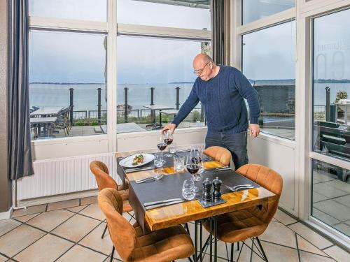 a man standing at a table with a glass of wine at 4 person holiday home on a holiday park in Faaborg in Faaborg