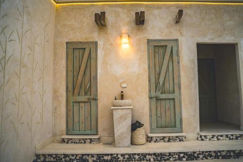a building with two green doors on the side at Asfay Lodge Siwa in Siwa
