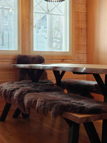 a wooden table with a faux fur bench and a wooden table with a tableablish at Holiday Cabin Naalinpesä incl Wifi, outdoor jacuzzi for extra fee in Äkäslompolo