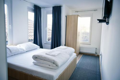 a bedroom with a bed with white sheets and two windows at Motel Alibi in Banja Luka