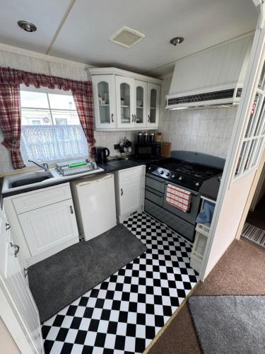 a small kitchen with a black and white checkered floor at Home from home in Ingoldmells