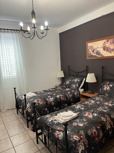 a bedroom with two beds and a chandelier at B&B Pokerdassi in Leonforte