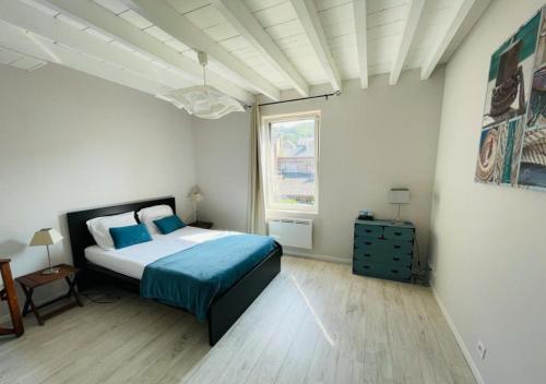 a bedroom with a bed with blue sheets and a window at Maison de pêcheur in Étretat