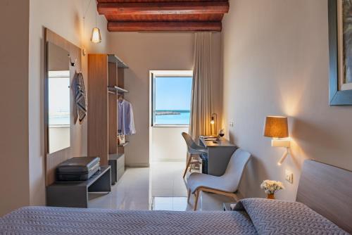 a hotel room with a bed and a desk and a window at Hotel Aliai in Sciacca