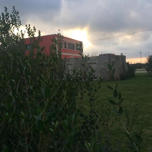 a building in a field with the sunset in the background at Tenuta Monaci La Murra in Carmiano