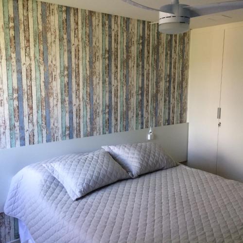a bedroom with a white bed with a floral wallpaper at Flat Carneiros Beach Resort in Tamandaré