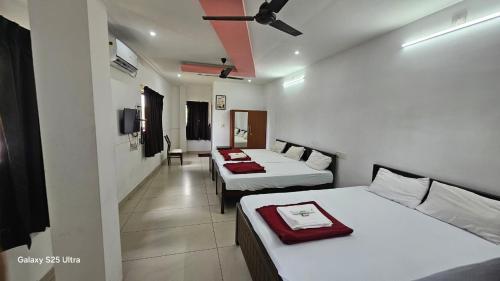 a room with two beds and a tv in it at Sky Residency Lodge in Trichūr
