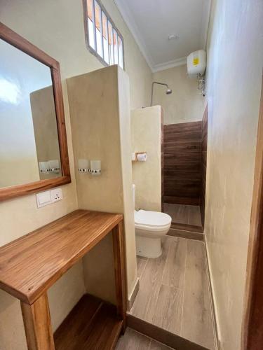 a bathroom with a toilet and a sink and a mirror at Meat and Mingle Tavern in Paje