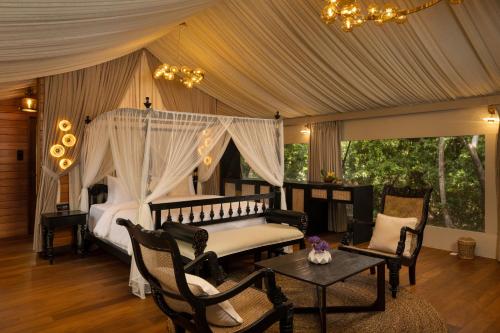 a bedroom with a canopy bed with chairs and a table at AARAWILD Luxury Villas - Sigiriya in Sigiriya