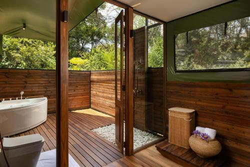 a bathroom with a wooden deck with a toilet and a tub at AARAWILD Luxury Villas - Sigiriya in Sigiriya