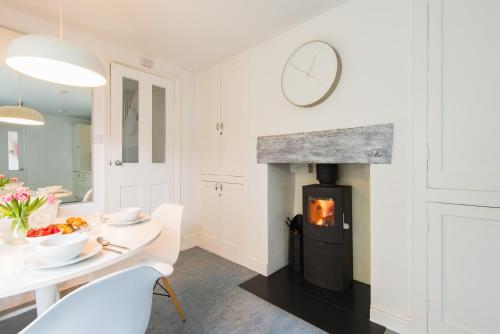 a living room with a fireplace and a table and a dining room at Captains Cottage in Deal