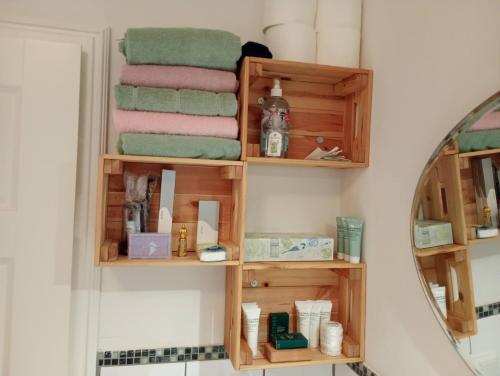 a bathroom with wooden shelves with towels and a mirror at Cottage Living 2 in Leiblfing