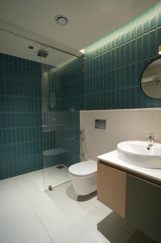 a green tiled bathroom with a toilet and a sink at Better Suites Hotel in Meppādi