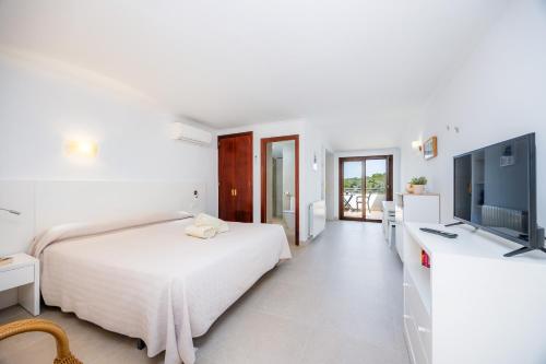 a white bedroom with a bed and a flat screen tv at Cala Figuera Studio 5b in Cala Figuera