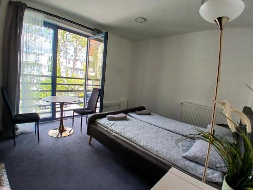 a bedroom with a bed and a table and a window at Pokoje w Centrum - Parking - Rowery in Sopot