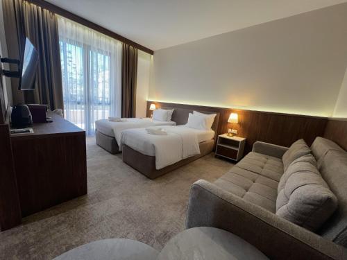 a hotel room with two beds and a couch at Hotel Onogošt in Nikšić