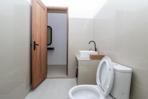 a white bathroom with a toilet and a sink at Mina Tanjung Hotel in Tanjung