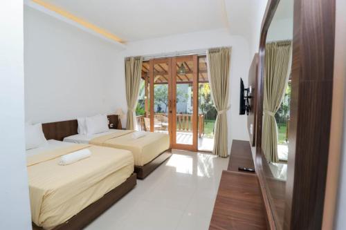 a bedroom with two beds and a glass door at Mina Tanjung Hotel in Tanjung