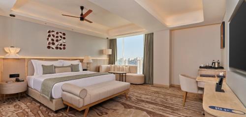 a bedroom with a large bed and a large window at The Forum Hotel and Convention in Ahmedabad