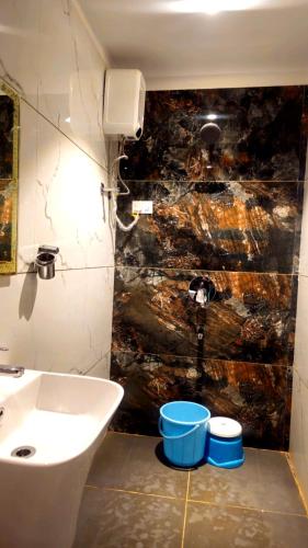 a bathroom with a sink and a toilet and a wall at Vardhan Lodge in Ajra
