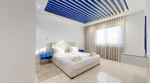 a white bedroom with a bed and a blue ceiling at Seven Floors in Tunis