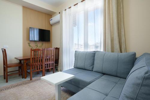 a living room with a blue couch and a table at Sea Vibe Apartment in Polisi i Vogël